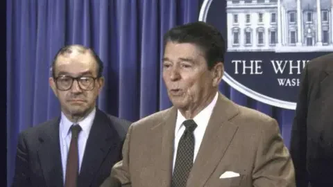 The Chronicle Collection via Getty Images Ronald Reagan and Alan Greenspan in 1987. They are standing at the podium in  the White House. President Reagan is speaking and Alan Greenspan is waiting to be introduced.